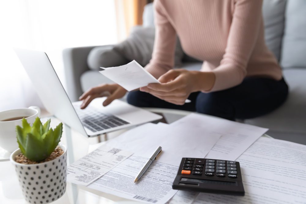 Crop close up of economical woman work on laptop at home pay bills taxes on gadget online,